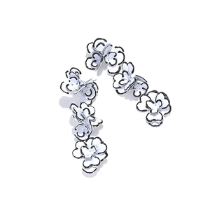 Close-up of long floral drop earrings with white enamel petals and black outlines