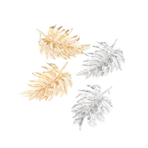 Detail of 3D alloy palm leaf earrings in polished gold and silver metallic finishes