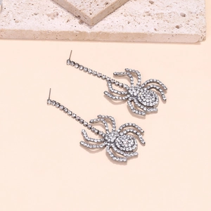 Sparkling rhinestone spider drop earrings on stone tray for Halloween fashion styling