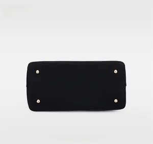 Détail du fond de sac noir mat avec quatre pieds de protection en métal doré brillant