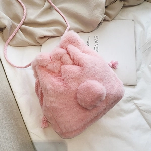 Pink faux fur drawstring bucket bag with cute pom-pom detail and woven shoulder strap