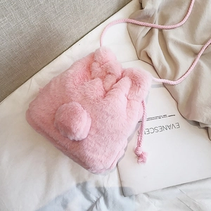 Pink faux fur drawstring bucket bag with soft pom-pom and woven strap for winter