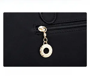 Gros plan sur la fermeture éclair dorée avec pendentif rond sur un sac noir élégant