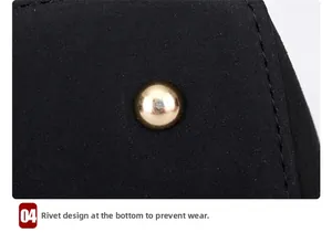 Gros plan sur les clous de protection dorés au bas d'un sac à bandoulière noir mat