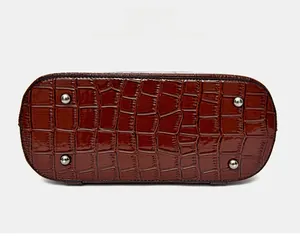 Detailed bottom view of reddish-brown crocodile pattern handbag with four metal protective feet