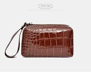 Detailed view of brown crocodile texture clutch with wristlet strap and metal zipper
