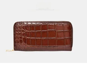 Close-up of brown long wallet with crocodile embossed texture and golden metal zipper