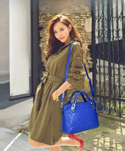 Detail of royal blue embossed leather handbag with metal hardware and round handle