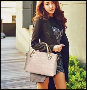 Chic beige handbag with textured embossing and gold ring handle held by model outdoors