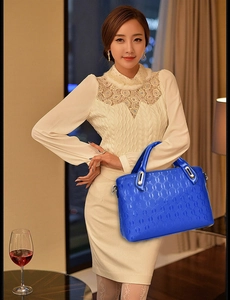 Close-up of royal blue handbag with chain embossed pattern and silver hardware detail