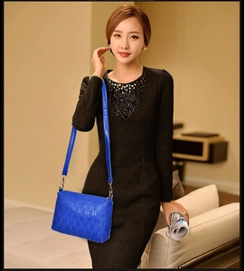 Blue crossbody bag with embossed ring texture worn by a model in a black dress