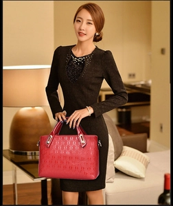 Close-up of glossy red handbag featuring embossed oval pattern and gold hardware details