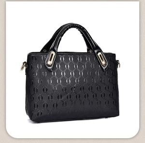 Close-up of black embossed faux leather handbag with circular textures and gold hardware