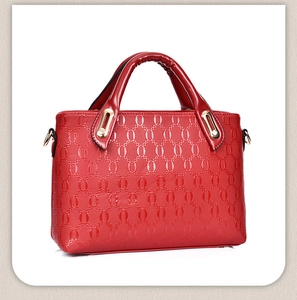 Detail of red textured handbag showing oval chain patterns and gold metal hardware