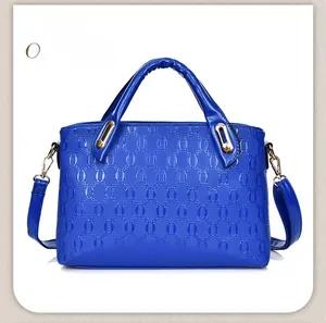 Detail of royal blue handbag with embossed ring pattern and gold hardware accents