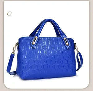 Detail of electric blue handbag with chain-embossed texture and golden metal hardware