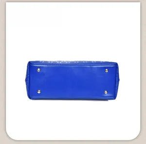 Detailed close-up of blue textured leather handbag base with four gold metal protective studs