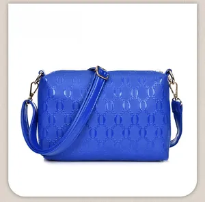 Detail of navy blue crossbody bag featuring interlocking ring embossed texture and gold hardware
