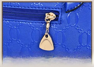 Detail of dark blue embossed leather bag with gold-plated zipper and triangular pendant