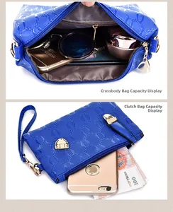 Detail view of deep blue crossbody bag capacity with smartphone and sunglasses inside