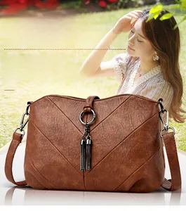 Détail d'un sac à bandoulière vintage marron avec coutures en V et pompons dorés