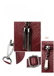 Détail du sac rouge à motif litchi avec fermetures éclair argentées et pendentifs à glands