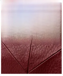 Détail macro du cuir synthétique bordeaux à texture litchi avec coutures géométriques