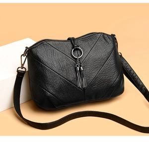 Détail du sac bandoulière en cuir noir avec anneau métallique et doubles glands