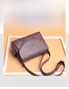 Détail du sac violet en cuir grainé avec logo kangourou et rabat de fermeture chic
