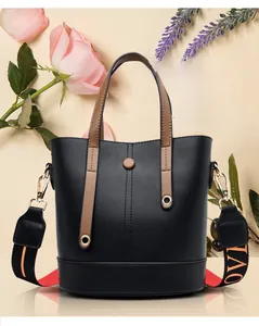 Detail of black leather bucket bag with brown handles and stylish LOVE patterned wide strap