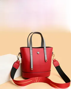 Detail of red PU leather handbag with LOVE print wide strap on geometric background