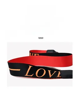 Detail of red and black crossbody bag showing LOVE print and leather strap connector