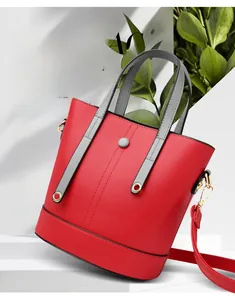 Detail of red leather bucket bag featuring grey contrast handles and gold hardware