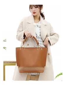 Dettaglio della borsa tote color cuoio con borchie metalliche e manici a catena dorata