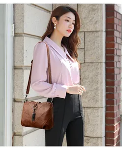 Détail du sac bandoulière vintage marron foncé avec anneau métallique et pompon en cuir