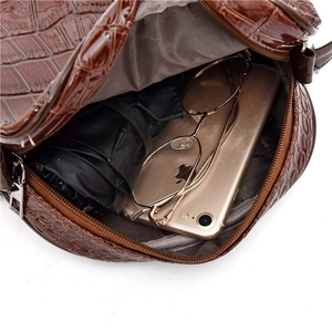 Brown crocodile pattern round crossbody bag showing spacious interior with personal items