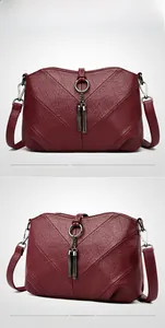 Détail du sac bandoulière bordeaux avec coutures en V et doubles pompons décoratifs