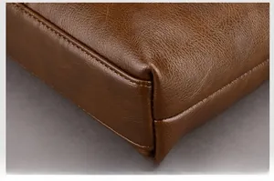 Close-up of brown leather bag corner showing durable double stitching and pebble grain texture