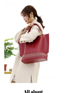 Borsa tote rossa in pelle con borchie dorate e manico a catena indossata