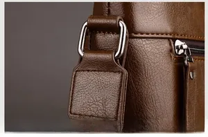 Close-up of durable silver D-ring hardware and textured brown leather on men's bag