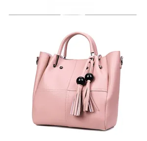Detailansicht der rosa Beuteltasche mit Quasten-Anhängern und Umhängeriemen