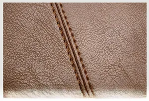 Detailed macro view of high-quality brown litchi grain leather and precision double stitching