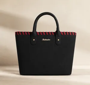 Close-up of black tote bag with red stitching details and gold hardware accents