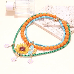 Dettaglio dei ciondoli a farfalla e girasole smaltati su una collana a più strati colorata