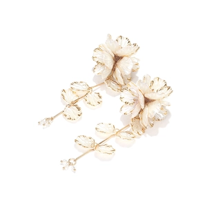 Detail view of handmade beaded flower earrings with gold leaf tassels and cream petals