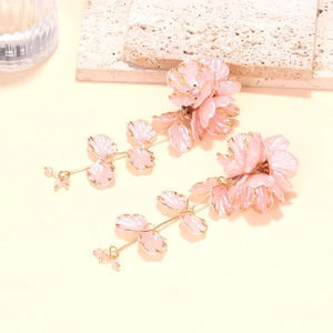 Detail of handmade beaded flower drop earrings with pink resin petals and gold tassels