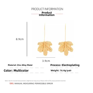Detailed view of long gold leaf pendant earrings with realistic texture and dimensions