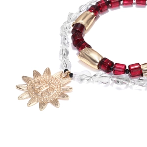 Detail of bohemian layered necklace with red beads and golden sun pendant close-up