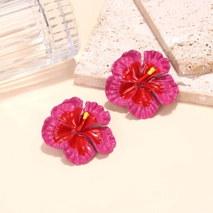Vibrant red and pink frangipani flower earrings with bold enamel finish on warm background