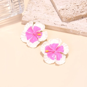 Detailed view of enamel frangipani earrings with pink gradient center on stone